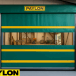 Creative use of roll-up vinyl door, high speed, featuring a green and yellow PAYLON roll-up door installed in a livestock and agricultural barn with a clear vision panel showing farming equipment inside