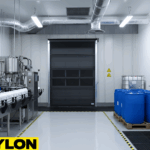 Black Roll Up Bug Door inside a chemical production area with equipment, storage drums, and marked safety zones.