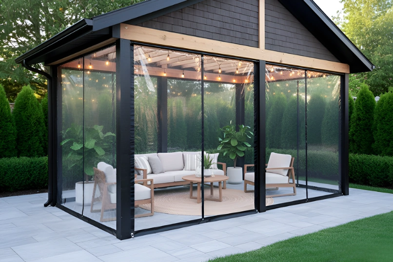 “Modern pavilion with clear vinyl curtain fully lowered, creating a cozy enclosed outdoor seating area with warm lighting.”