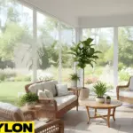 “Motorized clear vinyl curtains enclosing a bright sun room with wicker furniture and potted plants, showing a clear outdoor view.”