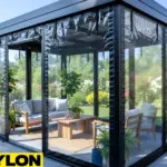 “Sun room with white-framed motorized clear vinyl curtains, comfortable seating, and lush greenery outside, illustrating year-round use.”