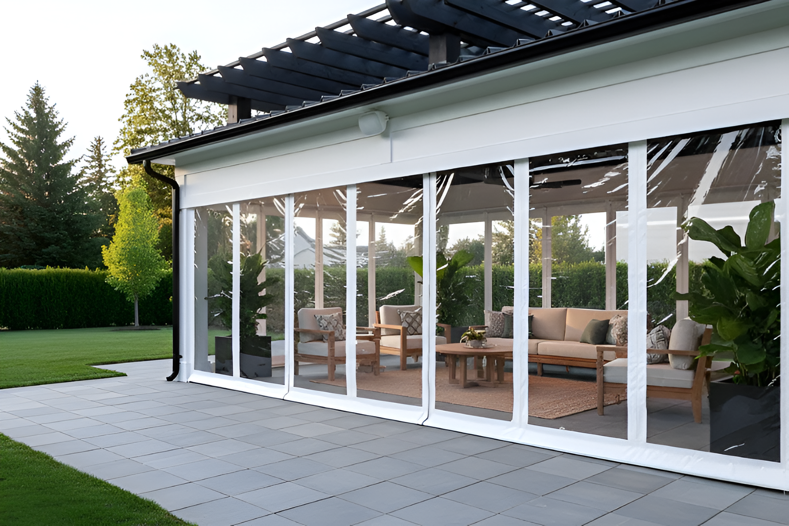 White-frame pavilion with motorized clear vinyl curtains lowered to enclose the space, creating a clean, bright outdoor rooms