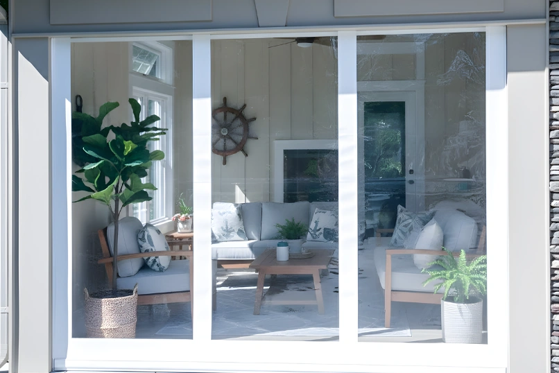 “White-framed motorized clear vinyl curtains enclosing a sun room, demonstrating protection from element while allowing natural light.”
