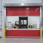 Red vinyl roll-up door separating machining and assembly areas inside a manufacturing room to support controlled workflow