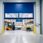 Roll-up vinyl door installed between warehouse aisles allowing forklift traffic and clear visibility