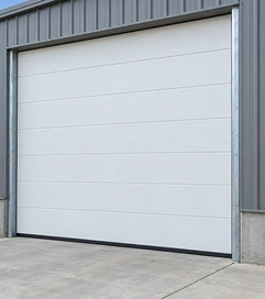 White insulated commercial garage door closed on a metal building