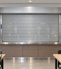 Vented roll-up counter door with perforated aluminum slats closed over a cafeteria service counter